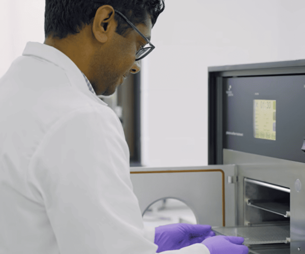 Scientist loading plasma treatment chamber for medical device surface activation in clean lab environment