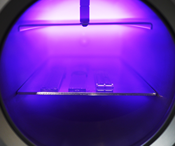 Oxygen plasma cleaning process inside a Henniker Plasma HPT-100 chamber showing purple plasma glow during surface treatment
