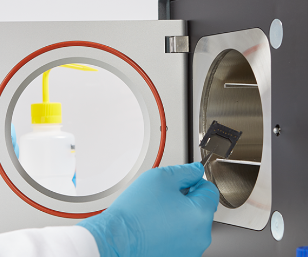 Front view of the Henniker Plasma HPT-200 plasma surface treatment system, featuring a purple-lit chamber and digital touchscreen interface for precision plasma processing and gene delivery.