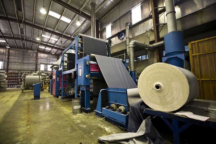 Industrial textile manufacturing machine with large fabric roll in factory, automated production and materials processing facility
