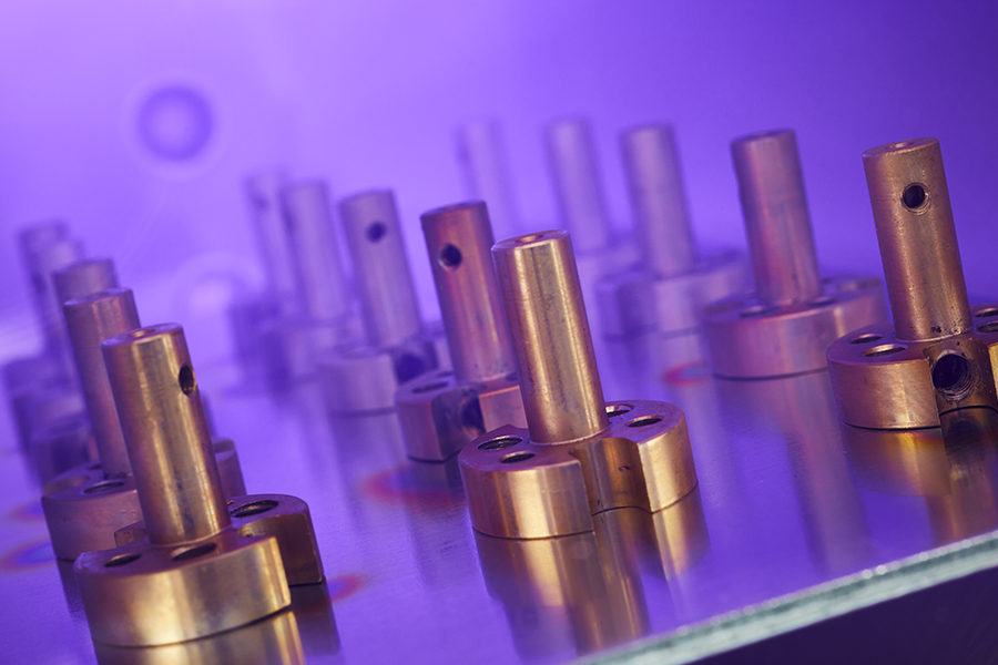 Precision machined metal components undergoing plasma surface treatment for improved adhesion and coating performance