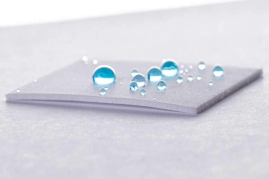Water droplets on coated metal surface demonstrating high contact angle and hydrophobic surface treatment performance