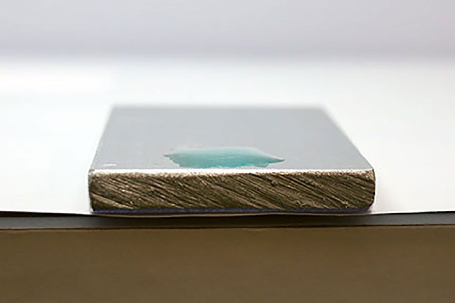 Water droplet on metal substrate demonstrating contact angle measurement and surface energy analysis in materials testing