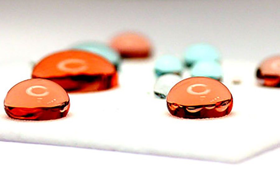 Coloured liquid droplets on polymer surface illustrating contact angle testing and surface wettability evaluation in materials science