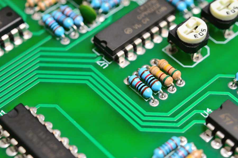 Close up of printed circuit board with resistors and integrated circuits, electronics manufacturing and PCB assembly concept