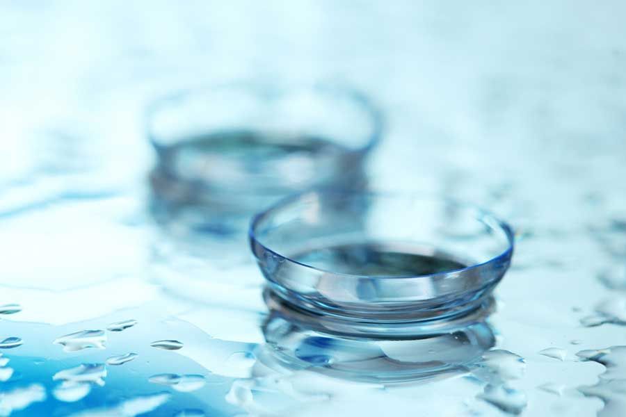 Contact lenses on wet surface with water droplets, ophthalmic materials and surface wettability testing concept