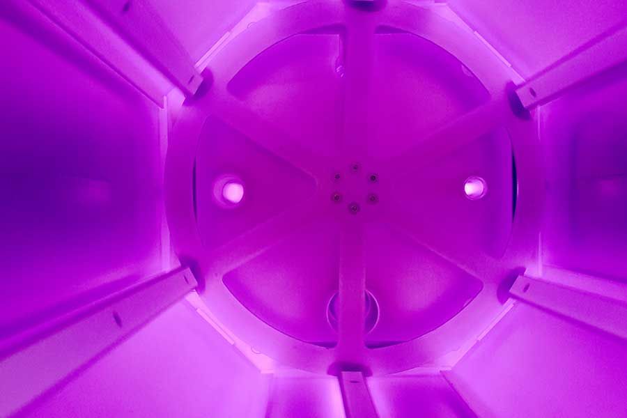 Inside vacuum plasma chamber with purple glow discharge, RF plasma surface treatment process for materials cleaning and activation