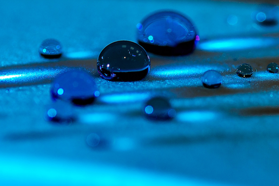 Water droplets on treated surface under blue light, hydrophobic coating performance and surface energy testing concept