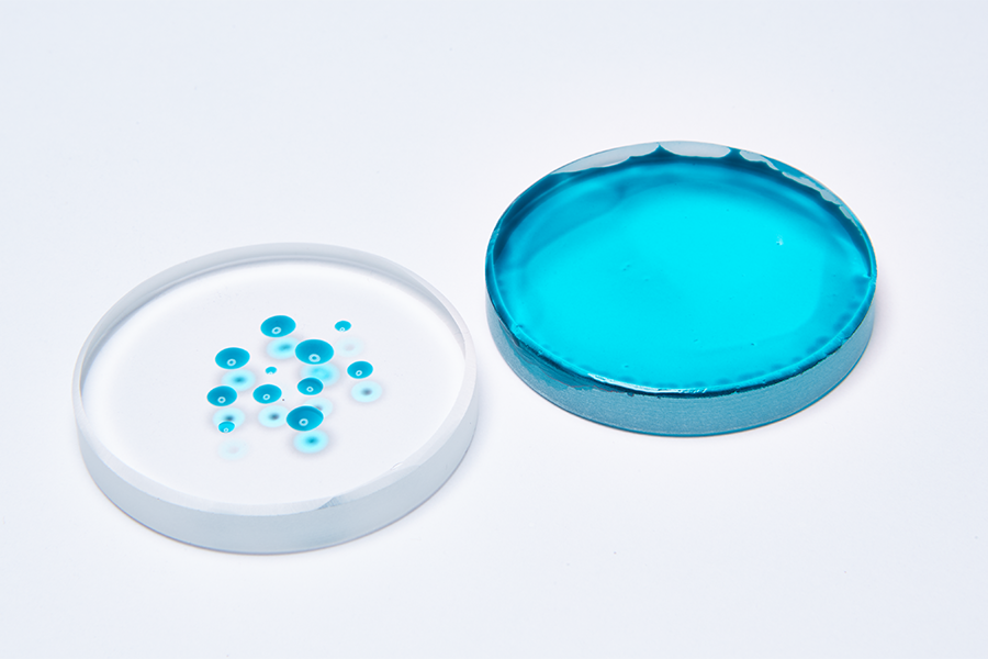 Petri dishes comparing untreated and plasma treated surfaces with blue test liquid, demonstrating surface energy and wettability improvement