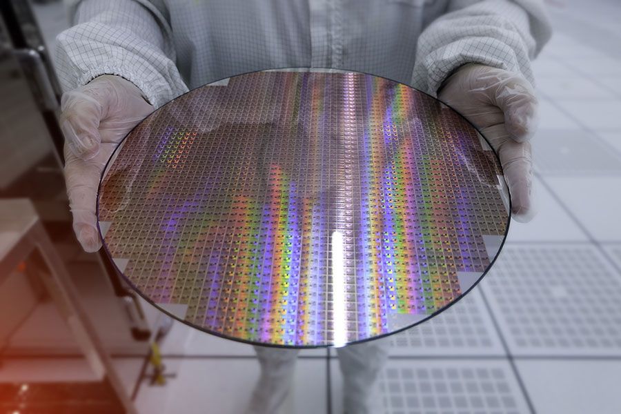 Semiconductor silicon wafer with microchip dies held in cleanroom environment for advanced electronics manufacturing